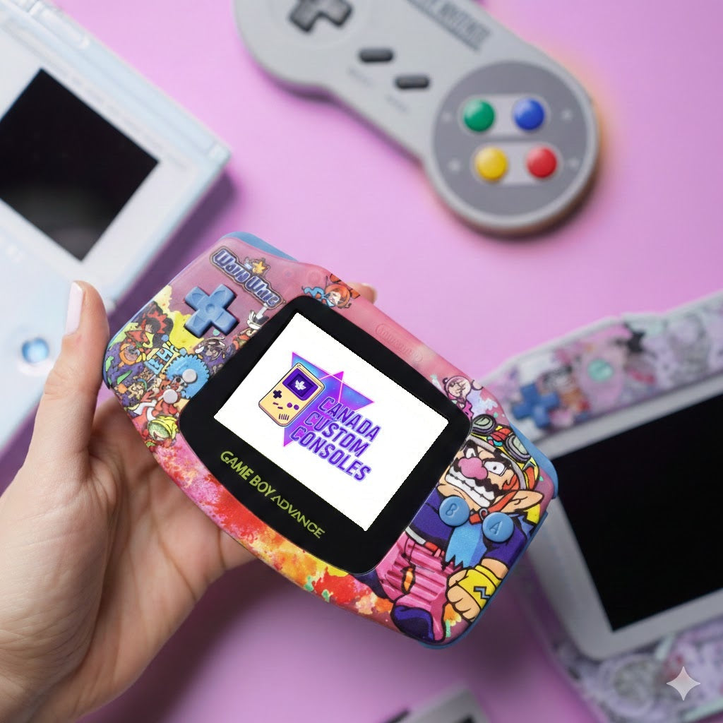 A hand holds a colorful, custom Game Boy Advance with cartoon designs. The screen displays Canada Custom Consoles. Retro gaming consoles are blurred in the background.