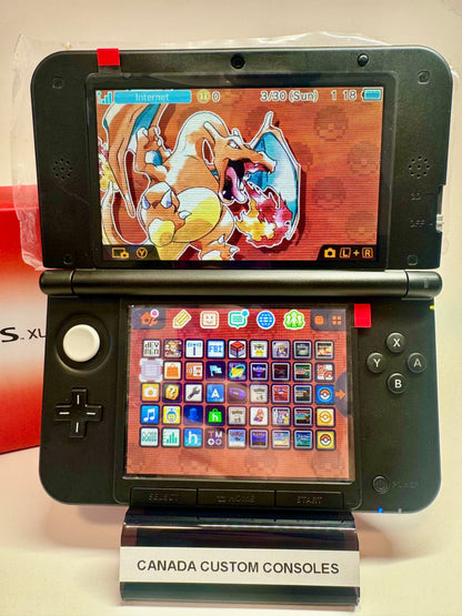 A red/black refurbished Nintendo 3DS XL—fully modded—features a Charizard-themed top screen, a colorful app icon grid, and sits on a stand labeled CANADA CUSTOM CONSOLES.