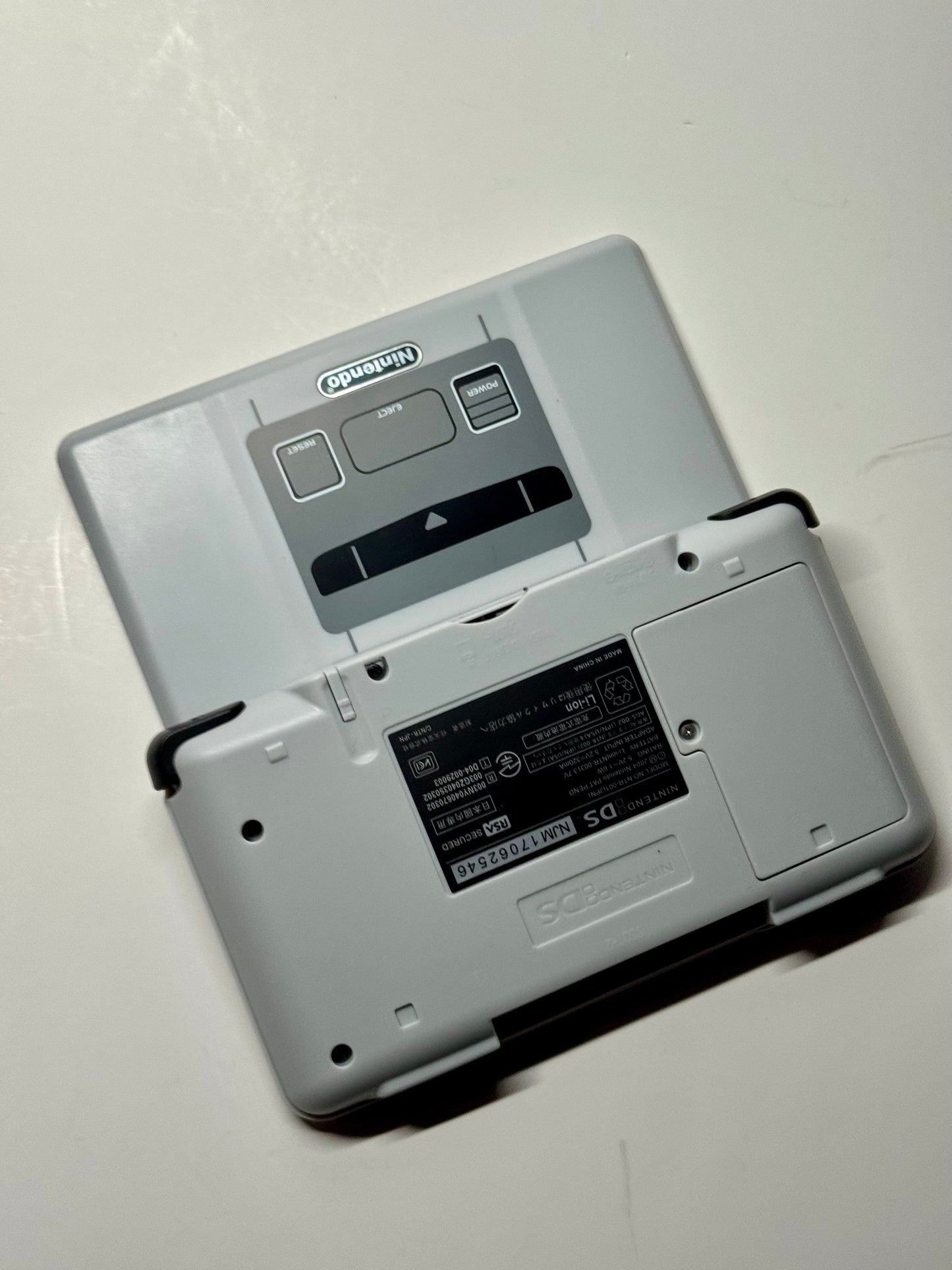 The Nintendo DS – SNES Edition features a Super Famicom-style shell and cover plate, displayed on a white surface. Its retro design closely resembles the classic look of a Super Famicom controller.