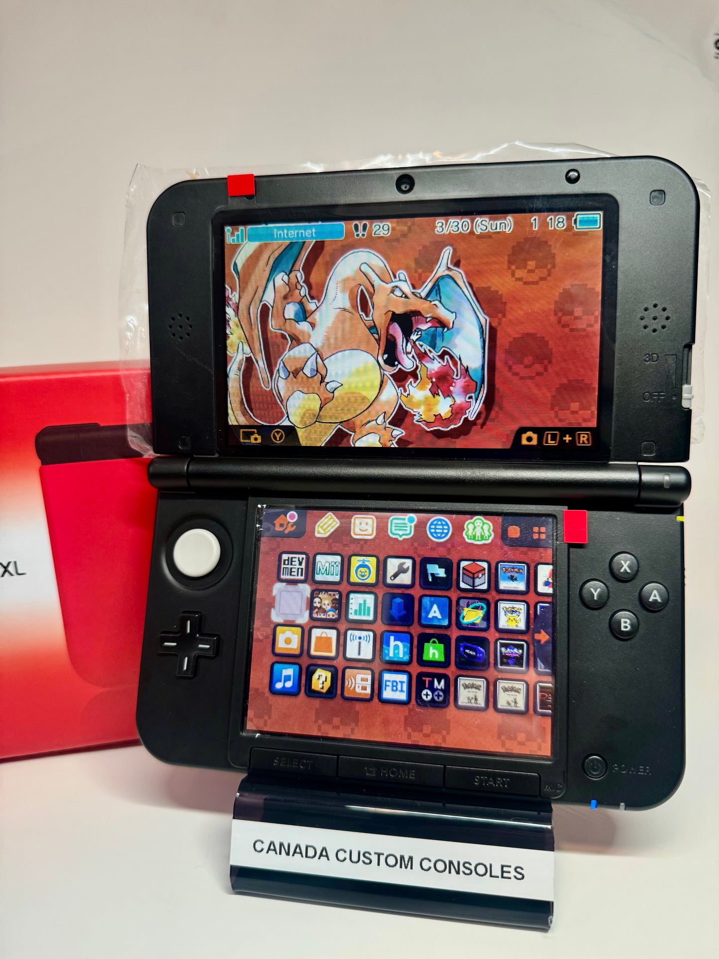 A refurbished Nintendo 3DS XL — Red/Black | Fully Modded is on display, open with a Charizard background on the top screen and colorful app icons below. A red box and CANADA CUSTOM CONSOLES stand are also visible.
