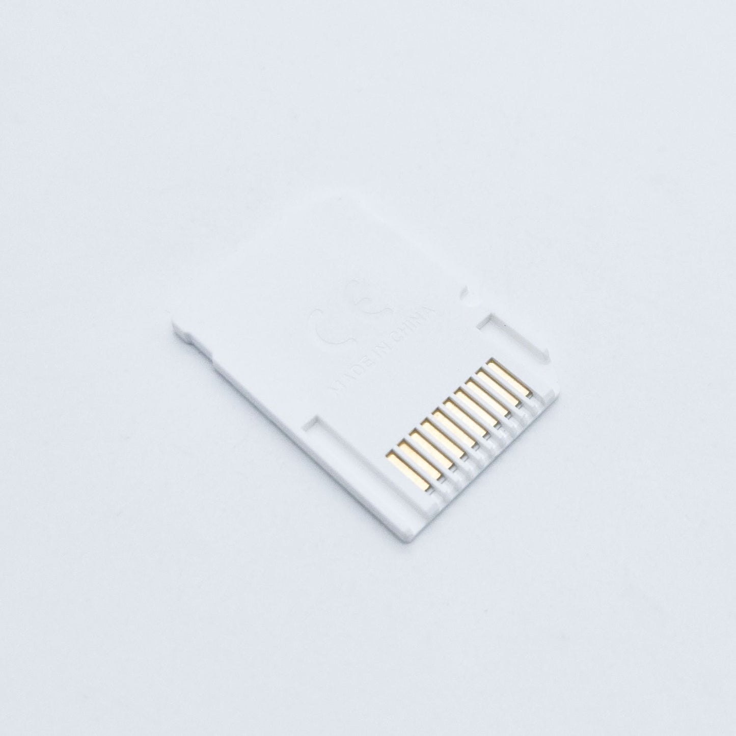 A white SD2Vita 5.0 MicroSD Adapter for PS Vita with gold connector pins rests on a plain white background, featuring faint "Made in China" text. Ideal for expanding storage using a MicroSD card on your PS Vita system.